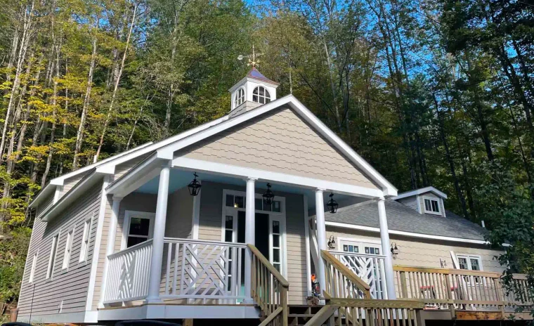 Custom timber frame home built by Level Headed Builders in Springfield VT with beige shake siding and a rooftop cupola