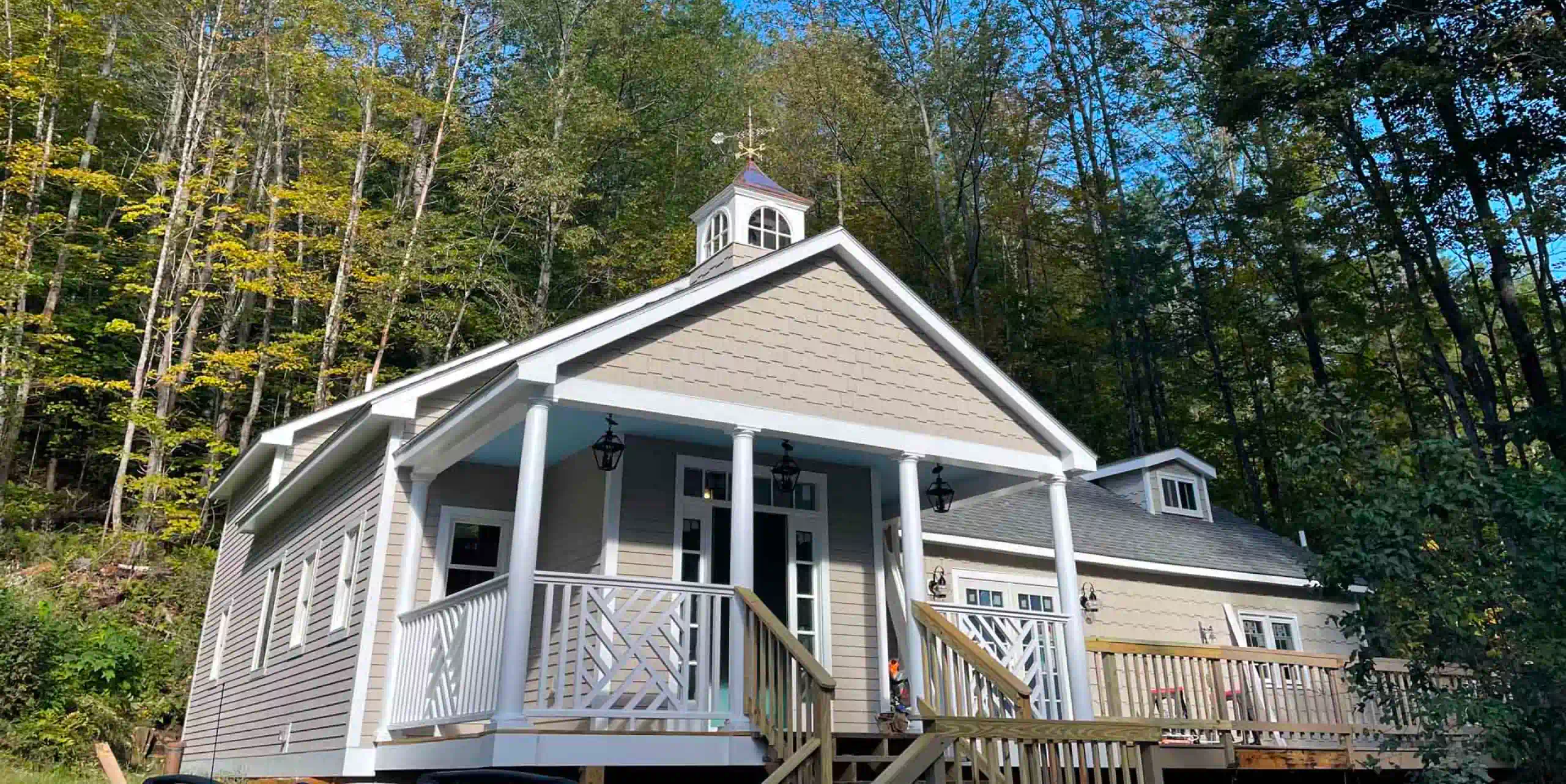 Custom timber frame home built by Level Headed Builders in Springfield VT with beige shake siding and a rooftop cupola