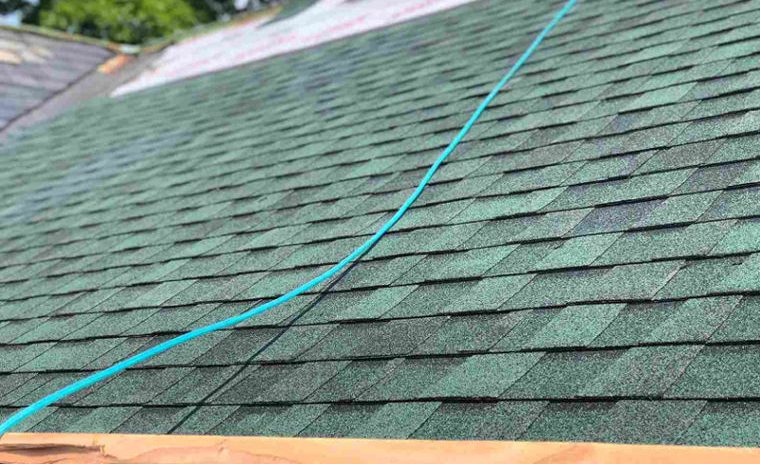 Custom home roof installation in progress by Level Headed Builders in Springfield VT with green asphalt shingles